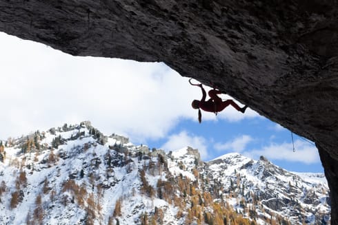 In silhouette, a Katie McKinstry Stylos climbs a nearly 90-degree overhanging roof.