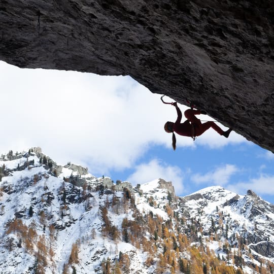 In silhouette, a Katie McKinstry Stylos climbs a nearly 90-degree overhanging roof.