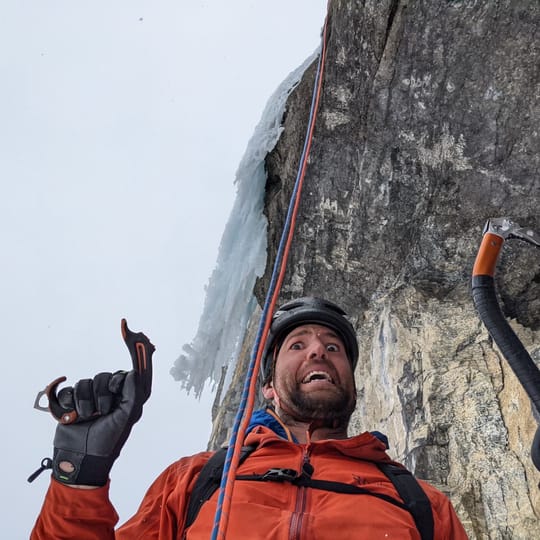 An ice climber showcases the broken handle of an ice tool. It's snapped where the rubber handle meets the aluminum shaft.